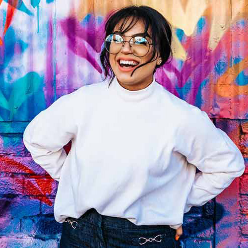 Photo d'une jeune fille qui rigole, sur un fond style street art